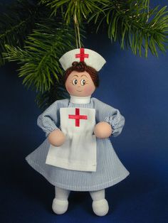 a christmas ornament with a nurse doll hanging from it's side on a tree branch