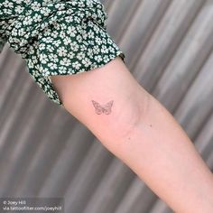 a small butterfly tattoo on the left inner arm and wrist, with white flowers all over it