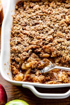 an apple crumbled dessert in a white casserole dish with a spoon