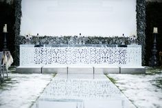 an outdoor ceremony set up in the snow with candles and flowers on it's side