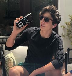 a young man sitting on top of a couch holding a cell phone