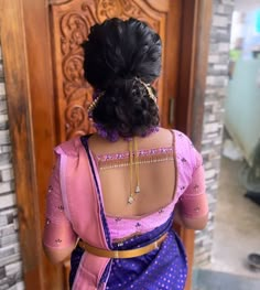 the back of a woman's pink and blue sari with gold jewelry on her neck