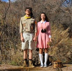 a man and woman dressed up in costume standing next to each other on a dirt road