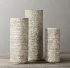 three white vases sitting on top of a wooden table