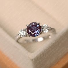 a purple and white diamond ring sitting on top of a box