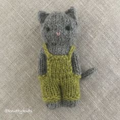 a knitted gray cat with yellow overalls