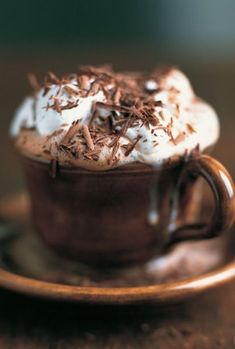 a cup filled with whipped cream and chocolate shavings on top of a saucer