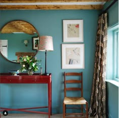 a room with blue walls and pictures on the wall, a red desk and chair