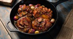 a pan filled with meat and vegetables on top of a wooden table