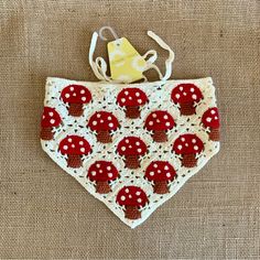 a red and white crocheted bib with mushrooms on it