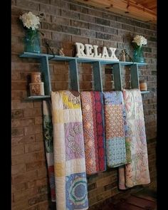 towels are hanging on the rack in front of a brick wall and there is a sign that says relax