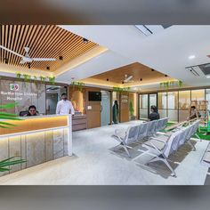 people are sitting at the reception desk in an office building with green plants on the ceiling