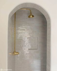 a white bathroom with gold fixtures in the shower