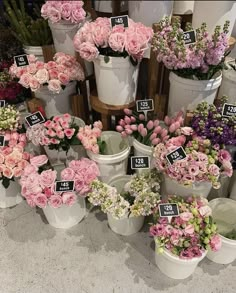 several buckets filled with pink and white flowers on display at a flower shop for sale