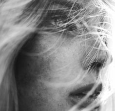 a black and white photo of a woman's face with hair blowing in the wind