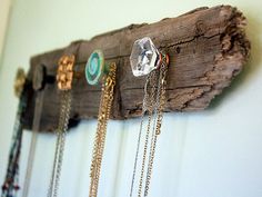 a wall mounted jewelry holder with chains hanging from it's sides