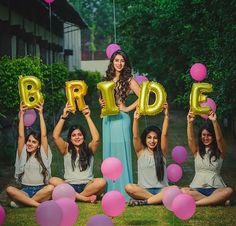 a group of women sitting on the ground holding up balloons