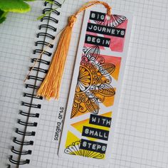 a bookmark with words on it and a tassel hanging from the end, next to a plant