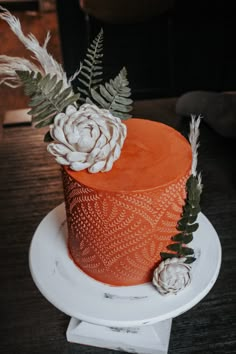 an orange cake decorated with flowers and leaves