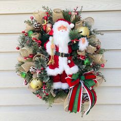 a christmas wreath with santa claus holding a bell and bells on it's front door