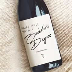 a bottle of wine sitting on top of a white cloth covered tablecloth with writing that reads paris well with a bachelor's degree