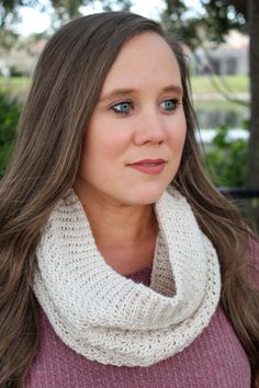 a woman with long hair wearing a white cowl scarf and looking at the camera