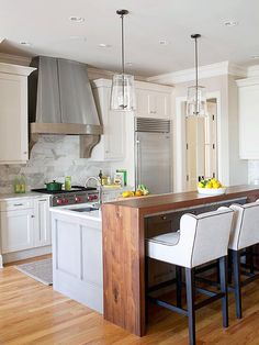 a kitchen with white cabinets and an island that has four bar stools in front of it