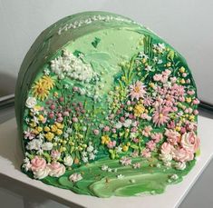 a green cake with flowers and butterflies on it