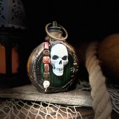 a pocket watch with a skull on it sitting next to a rope and lantern light