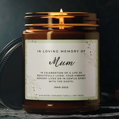 a candle that is sitting on top of a table next to a jar with the words in loving memory of mum