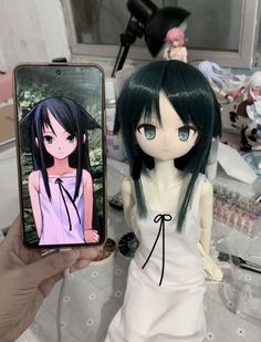 a doll holding up a cell phone with an anime character on it