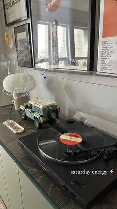 a record player sitting on top of a black counter next to a wall with pictures