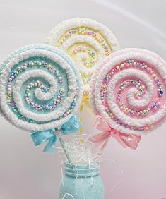 three lollipops are in a vase on a table with ribbons and beads