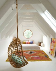 a room with a bed, rugs and a hanging chair in the middle of it