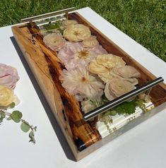 a wooden tray with flowers in it sitting on the ground