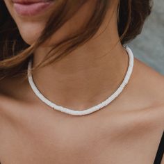 a woman wearing a white necklace on her neck