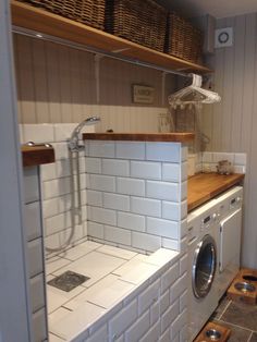 a washer and dryer in a small room with shelves on the wall behind them