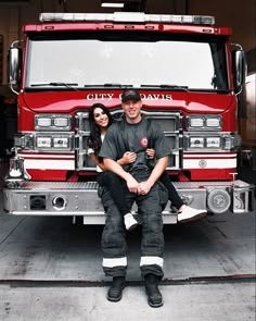 a man and woman sitting in front of a fire truck