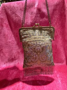 a small purse sitting on top of a pink velvet chair with chains hanging from it