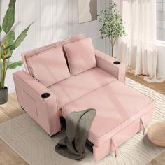 a pink couch sitting on top of a wooden floor next to a potted plant