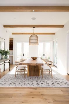 a dining room table with chairs and a rug on the floor in front of it