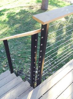 a wooden deck with metal railing and handrails in the grass next to a tree