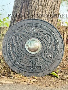 Viking Carved Wooden Shield, Norse Viking Shield Gifts, Wall Decor Carving Shield, Viking Cosplay & Costume Gifts Carved Viking Wooden Shield Bring a piece of Viking heritage to your home, collection, or reenactment gear with this authentic-style Viking shield. Each shield is meticulously carved and crafted, reflecting the strength and artistry of Norse warriors. Ideal for collectors, reenactors, or as an impressive decorative piece. Product Description: *Material: high-quality wood with a durable stain and protective finish. *Design: Features intricate carved Viking symbols or patterns, such as knotwork, runes, or a stylized Norse dragon. Finished in natural wood tones, enhancing the shield's historical  *Size:24" diameter for standard display, 30" diameter for larger impact, *Weight: Lig Norse Dragon, Viking Heritage, Viking Cosplay, Wooden Shield, Viking Shield, Viking Symbols, Norse Vikings, Wood Tones, Cosplay Costume