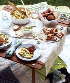 an outdoor table with plates of food and drinks on it, including meatballs and pasta