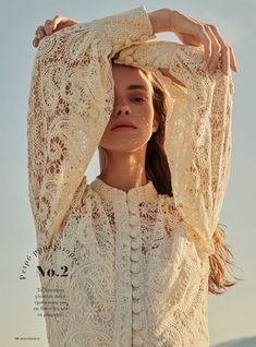 a young woman is posing for the camera wearing a white lace blouse and jeans with her hands on her head