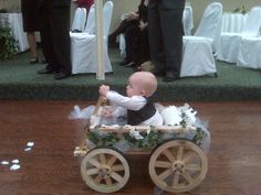 a baby in a wagon with an umbrella on the floor and people standing behind it