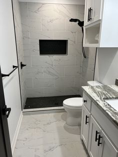 a white toilet sitting in a bathroom next to a walk in shower and counter top