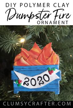 a diy polymer clay dumpster fire ornament hanging from a christmas tree