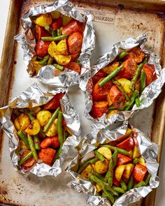 four trays filled with cooked vegetables on tin foil