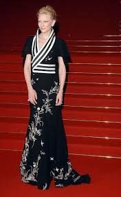 a woman standing on top of a red carpet wearing a black and white dress with flowers